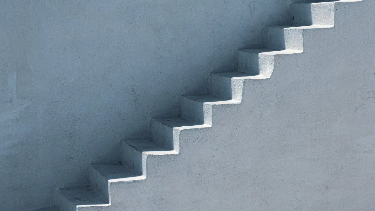 a flight of white steps in bright sunlight with a hard shadow falling across them