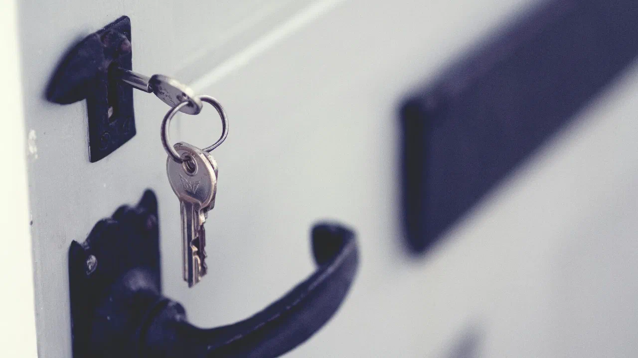 a key left in the lock of a white door with a black handle