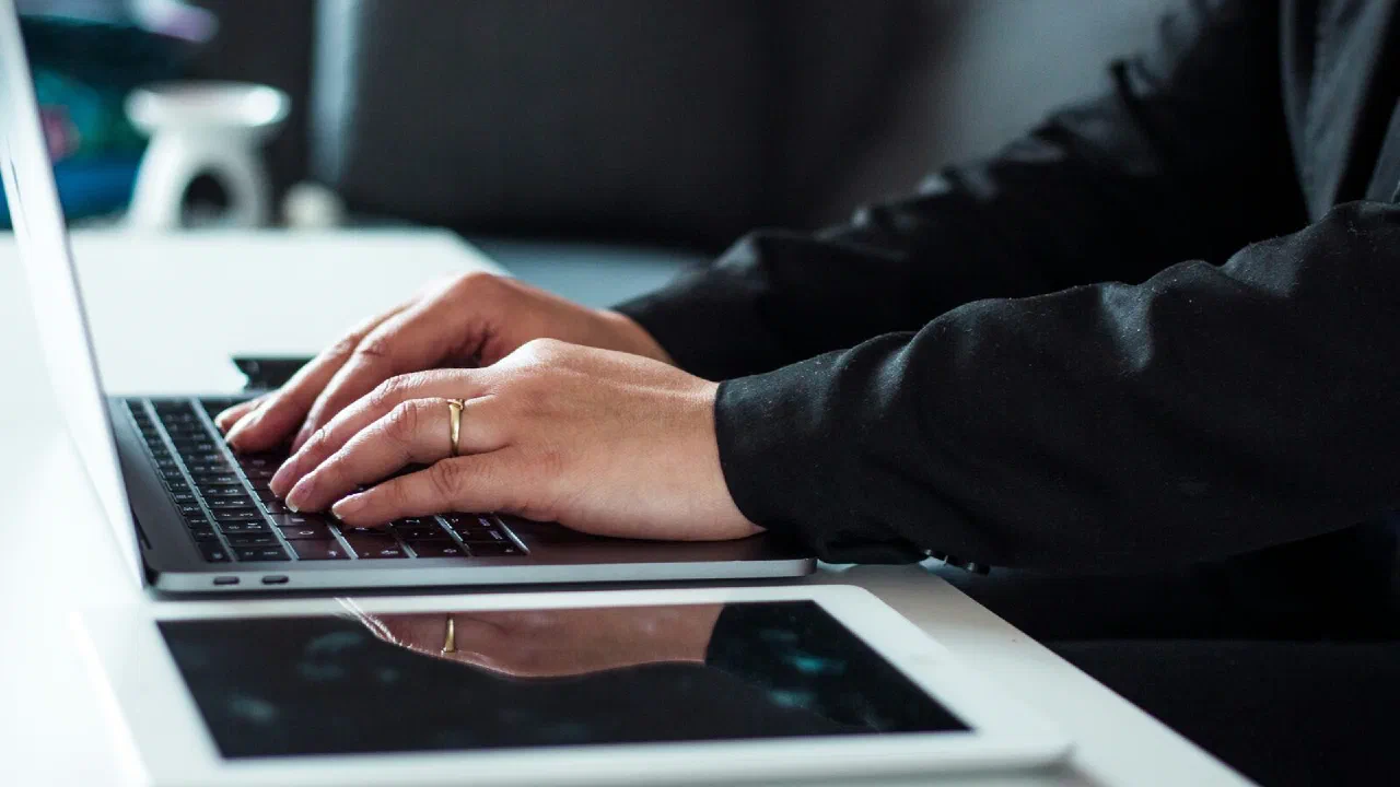 A person in a dark shirt working at a laptop