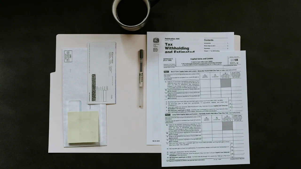 printed forms, a pen and a coffee mug on a dark desk